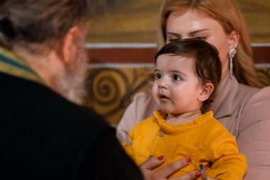A touching family moment during an indoor church event, showing a child held by a parent.